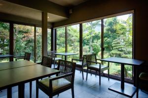 a restaurant with tables and chairs and a large window at Ryokan Yoshidaya in Ureshino