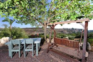 a picnic table and a bench under a tree at Shangri-Hila Lodge in Mitzpe Hila