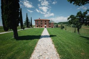 Casale in Collina في Capriva del Friuli: منزل على حقل عشبي مع طريق حصى