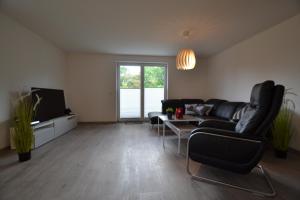 ein Wohnzimmer mit einem schwarzen Sofa und einem TV in der Unterkunft Ferienhaus Gammendorf Nr. 18 in Fehmarn