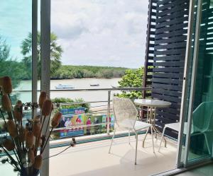 balcón con mesa, sillas y vistas al río en Krabi River View Hotel en Krabi