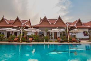 un complejo con una piscina con sillas y sombrillas en RaVorn Villa Boutique, en Battambang