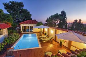 ein Haus mit einem Pool auf einer Terrasse mit Sonnenschirmen in der Unterkunft Villa Gloria in Dubrovnik