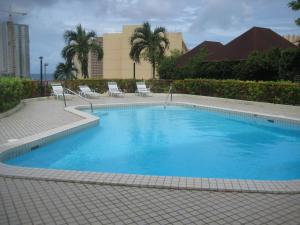 une grande piscine bleue avec des chaises et des palmiers dans l'établissement Tumon Bay Capital Hotel, à Tumon