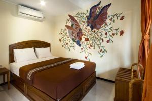a bedroom with a bed with a painting on the wall at De Hostel Yogyakarta in Yogyakarta