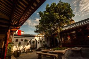 a courtyard with benches and a tree in front of a building at Manju Inn in Chaozhou