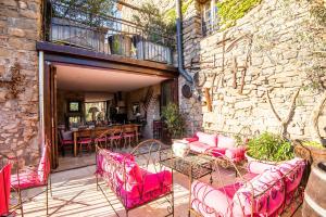 un patio avec des chaises et des tables roses et un mur en pierre dans l'établissement Chambre et Gite Le Roc sur l'Orbieu, à Carcassone