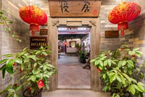 an entrance to a building with red lanterns and plants at Manju Inn in Chaozhou