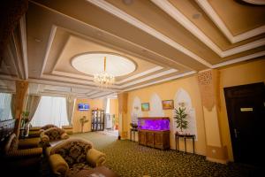 タシュケントにあるグロリア ホテルのシャンデリアとテレビ付きの広いリビングルーム
