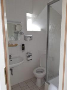 a white bathroom with a toilet and a sink at Leutloff's am See in Zeuthen