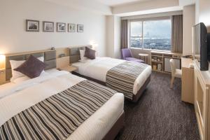 a hotel room with two beds and a television at Art Hotel Osaka Bay Tower in Osaka