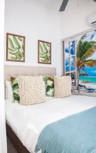 a bedroom with a large white bed and a window at Palm Cottage in Durban