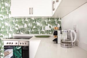 a kitchen with white cabinets and a blender on a stove at Palm Cottage in Durban