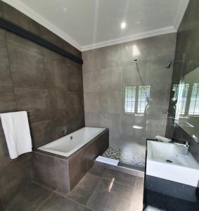 a bathroom with a bath tub and a sink at La Orchard Hotel in Johannesburg