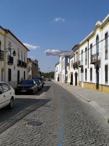 a cobblestone street with cars parked on the side at Casa da Lagoa Guest House in Évora