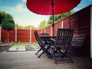 a table and chairs with a red umbrella on a deck at Paul's Place near Heathrow in London