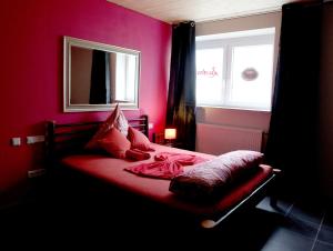 Dormitorio rojo con cama y ventana en Stundenhotel Lustra, en Landshut