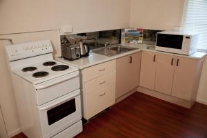 a kitchen with a white stove and a microwave at Strand Motel in Townsville
