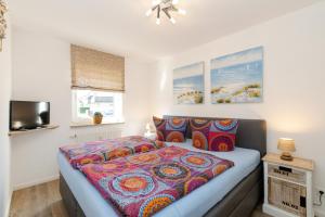 Schlafzimmer mit einem Bett mit bunter Bettwäsche und einem TV in der Unterkunft Ferienwohnung Ulber in Westerland