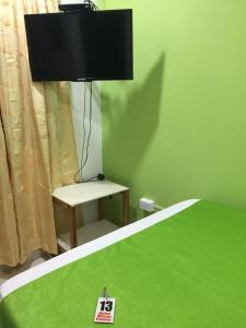 ein grünes Schlafzimmer mit einem Bett, einem Tisch und einer Lampe in der Unterkunft Hotel Miami center in Montería
