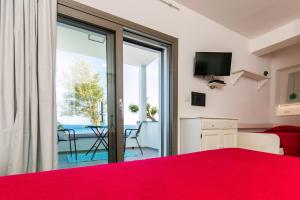 a bedroom with a red bed and a view of the ocean at Appartamenti Jlune in Cala Gonone