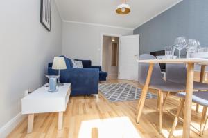ein Wohnzimmer mit einem Tisch und blauen Stühlen in der Unterkunft CR Rodzinny Apartament Chrobrego 16 in Białystok