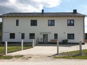 ein weißes Haus mit einem Zaun davor in der Unterkunft Steinackerhof in Burgthann