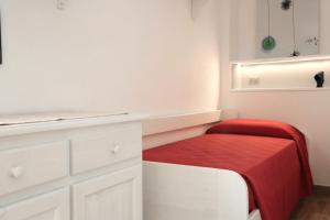 a small white kitchen with a red blanket on a stool at Appartamenti Jlune in Cala Gonone