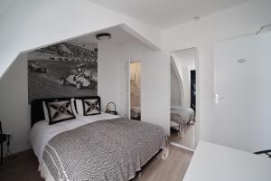 a white bedroom with a bed and a mirror at Hotel Zeespiegel in Zandvoort