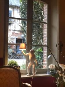 a stuffed monkey sitting on a window sill holding a lamp at La Cour Sainte Catherine demeure de charme in Honfleur