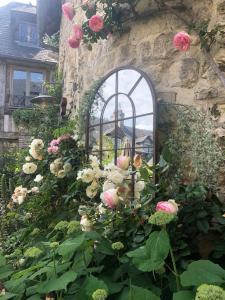 La Cour Sainte Catherine demeure de charme في أونفلور: حفنة من الورود أمام جدار حجري