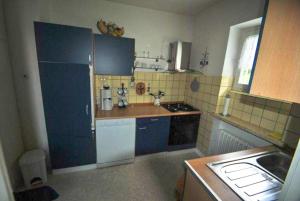 eine Küche mit blauen Schränken und einem weißen Kühlschrank in der Unterkunft Haus Rehblick FeWo-EG-1 in Sankt Andreasberg