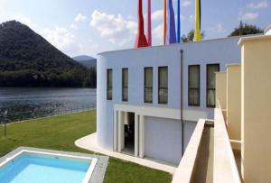 a building with a swimming pool next to a body of water at Hotel Miralago in Piediluco