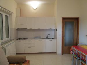 Apartments Villa Fernetich في بريمونتيرا: مطبخ بدولاب بيضاء ومغسلة وطاولة