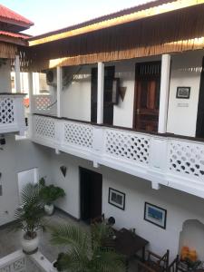 a white building with a balcony with a table and chairs at zLife Stone Town in Zanzibar City