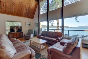 a living room with leather furniture and large windows at Lopez Island Hunter Bay Waterfront Home in Lopez
