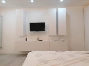 a white bedroom with a flat screen tv on the wall at White studio in Cluj-Napoca