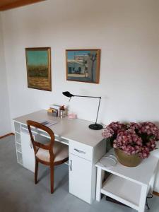 a desk with a chair and a lamp and flowers at My sweet home in Sauerlach