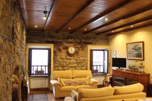a living room with two couches and a stone wall at Cau la mar in Lastres