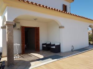 une maison blanche avec une porte ouverte et une terrasse dans l'établissement Hotel Il Platano, à San Teodoro