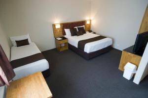 a hotel room with two beds and a television at Noah's Mid City Motor Inn Muswellbrook in Muswellbrook