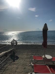 a beach with chairs and an umbrella and the ocean at Casa del sasso in Bergeggi