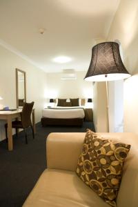 a hotel room with a bed and a couch and a lamp at Noah's Mid City Motor Inn Muswellbrook in Muswellbrook