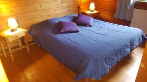 a bedroom with a bed with purple sheets and two lamps at Domaine du Hulobiet in Fromelennes