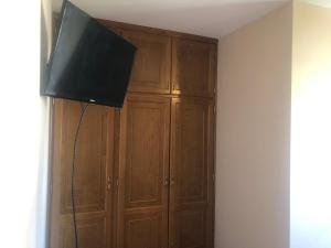 a flat screen tv hanging on a wall next to wooden cabinets at H Rural Chamouco in Bóveda
