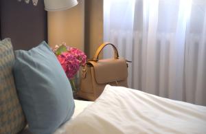 a purse and a vase with flowers on a bed at Lizz Hotel Munich in Munich
