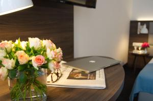 a vase of flowers on a table with a laptop at Lizz Hotel Munich in Munich