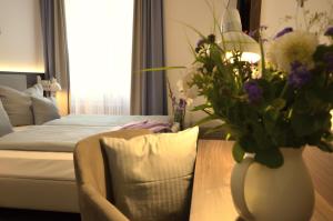 a bedroom with a bed and a table with a vase of flowers at Lizz Hotel Munich in Munich