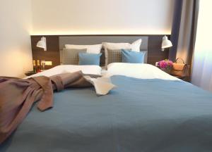 ein Schlafzimmer mit einem großen Bett mit einer blauen Decke in der Unterkunft Lizz Hotel Munich in München