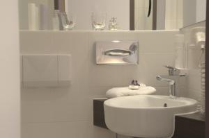 a white bathroom with a sink and a mirror at Lizz Hotel Munich in Munich